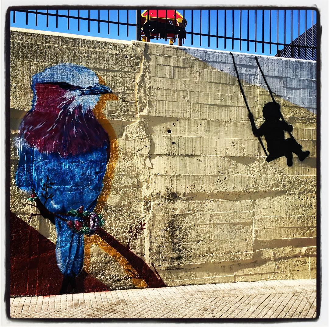 El colegio Escolapios, ubicado en el barrio vitoriano de Santa Lucía, presume de una extensa pintura en uno de los laterales del muro y la valla que delimitan su perímetro. Entre las numerosas figuras que se pueden apreciar, destaca este inmenso pájaro; que parece observar a la silueta que se columpia a su lado.