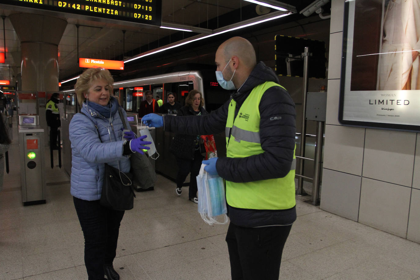 Un voluntario de la DYA entrega mascarillas a la entrada de la estación de La Arenas.
