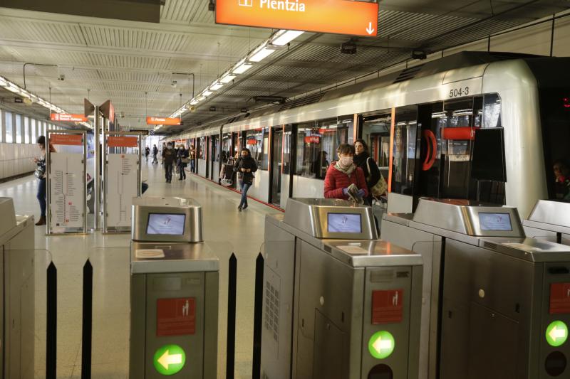 Un voluntario de la DYA entrega mascarillas a la entrada de la estación de La Arenas.