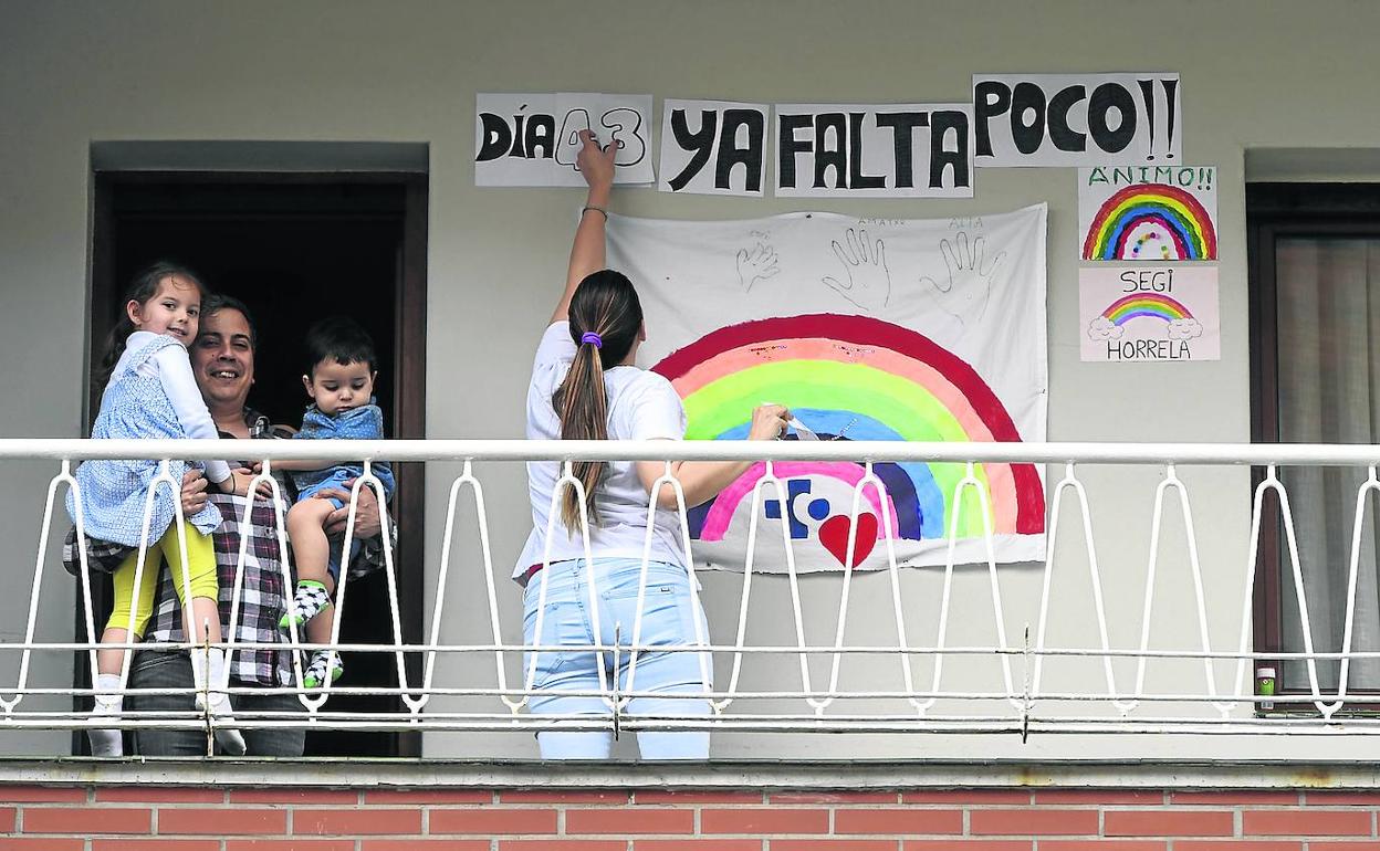 Un padre se asoma con sus pequeños al balcón de su vivienda en el barrio baracaldés de Cruces.