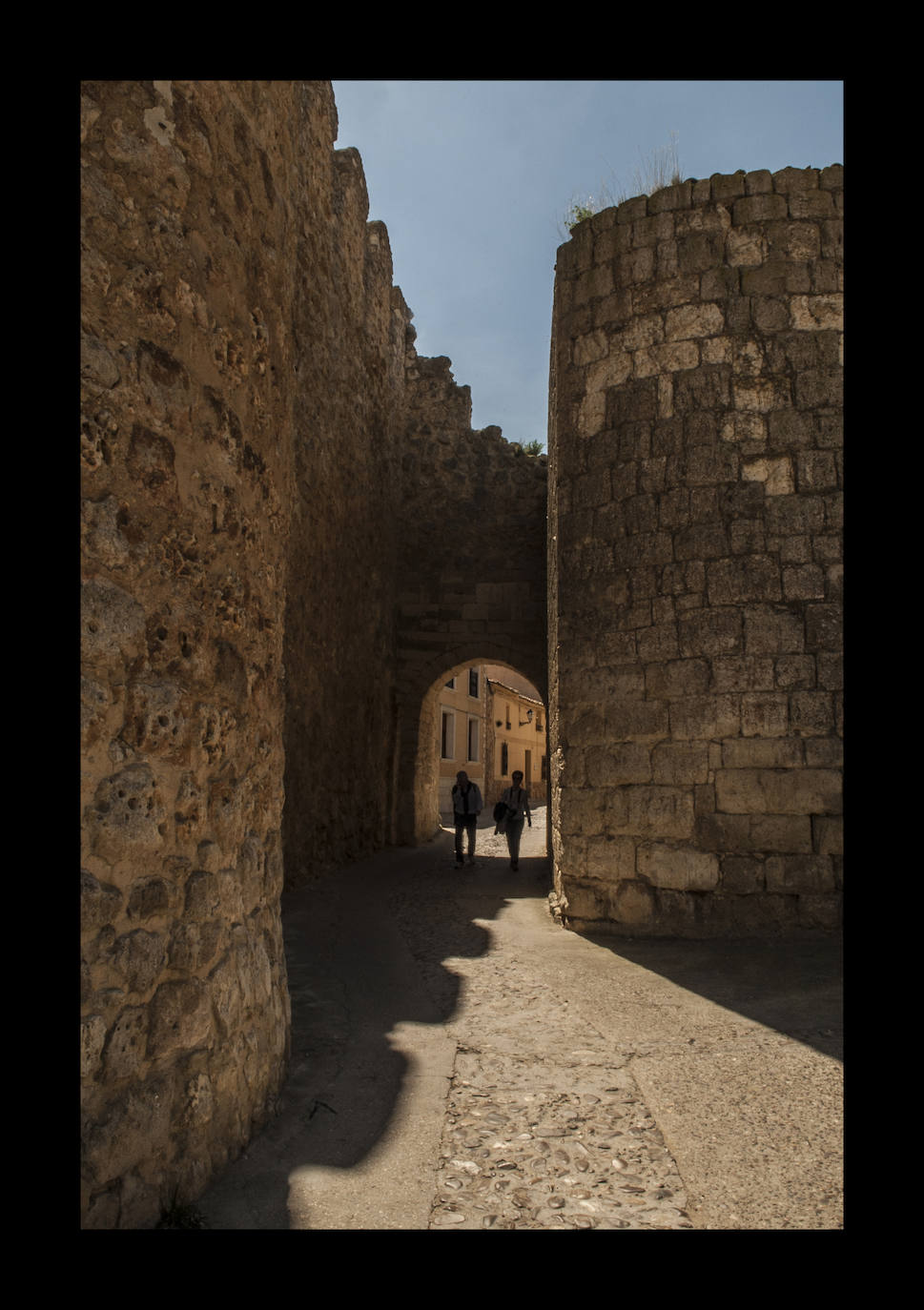 A Urueña, encaramada en un otero y rodeada de murallas, se la conoce como la Villa del Libro, un proyecto d ela Diputación de Valladolid que concentra una docena de librerías, aunque no todas abren a diario. Cuenta con uno de los cascos medievales mejor conservados de toda España y fue declarado Conjunto Histórico Artístico en 1975. En la imagen, dos transeúntes pasan bajo la conocida como Puerta del Azogue.