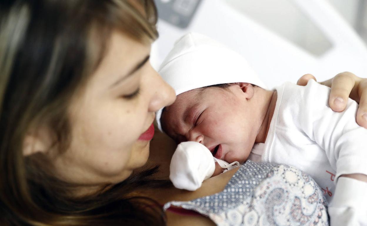 Una mujer, con su bebé recién nacido.