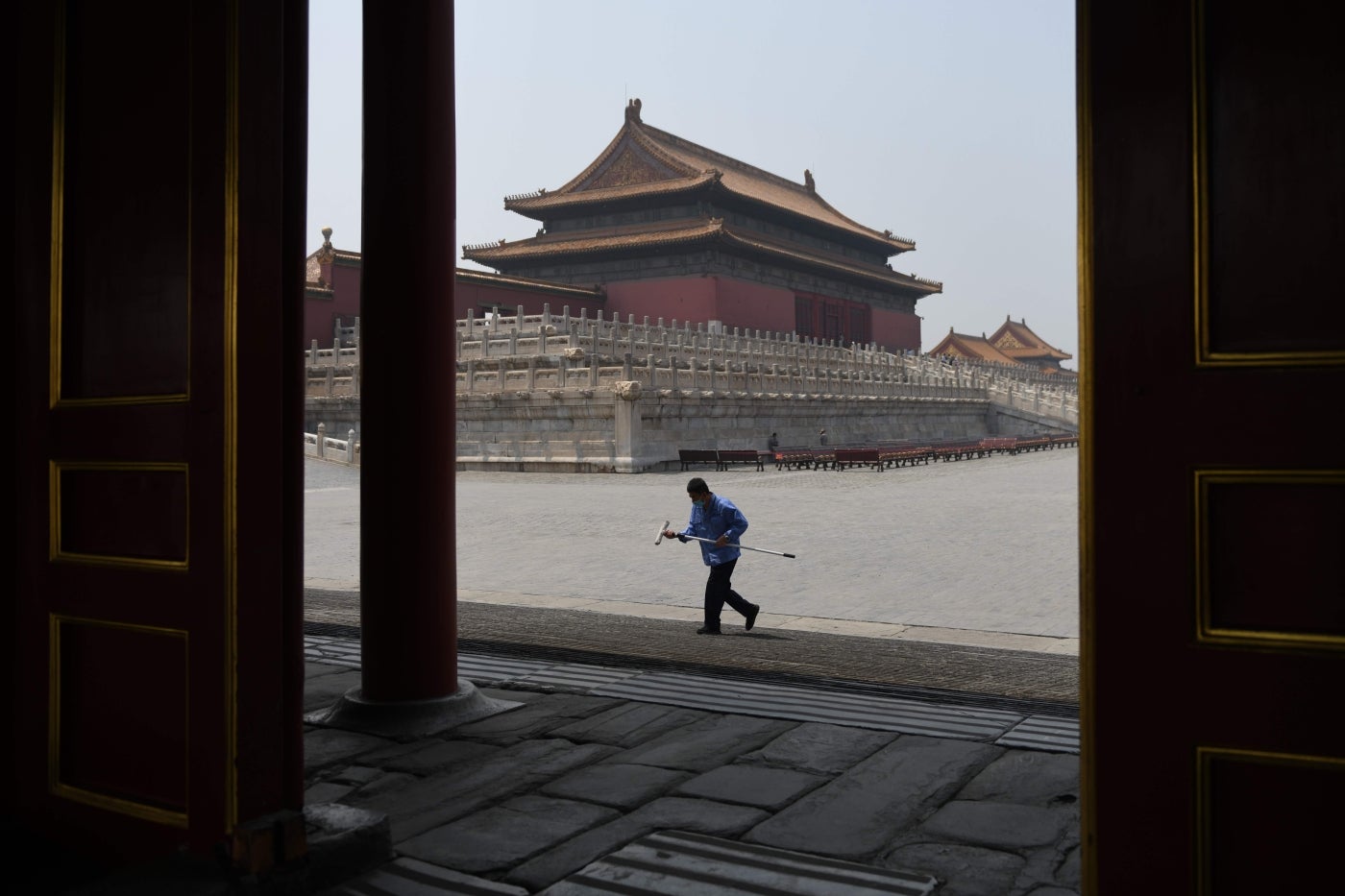 Un limpiador usa una mascarilla como medida preventiva contra el coronavirus COVID-19 mientras camina en la Ciudad Prohibida, el antiguo palacio de los emperadores de China, en Beijing. 