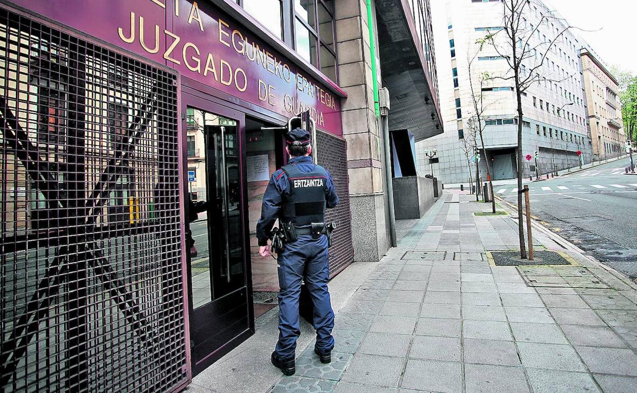 Un ertzaina protege la entrada del juzgado de guardia de Bilbao, la única instancia judicial que funciona a pleno rendimiento en la crisis.