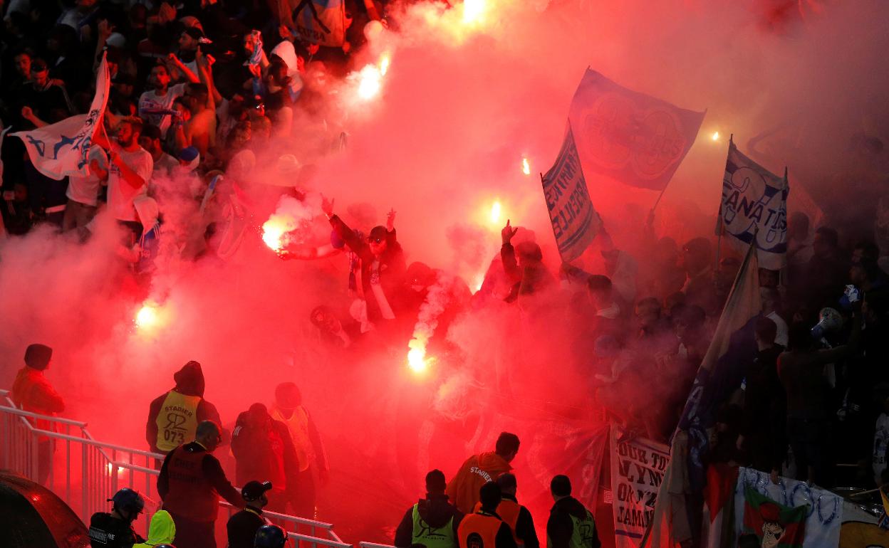 Aficionados del Olympique encienden bengalas. 