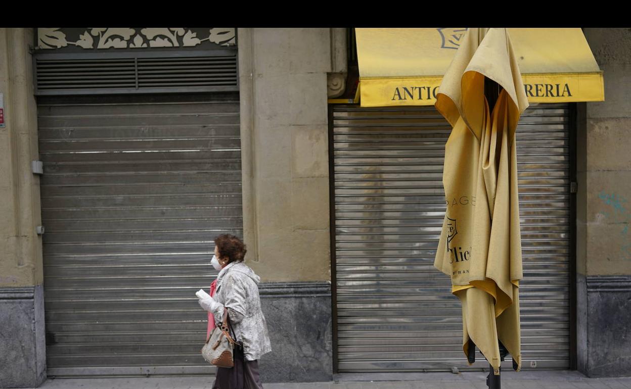 Una mujer pasa por delante de varios establecimientos cerrados en una calle de Bilbao. 