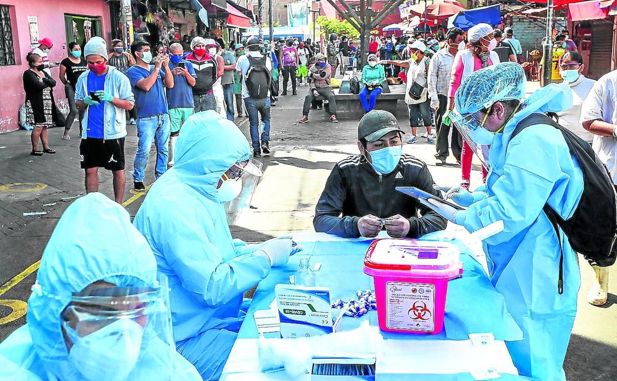Trabajadores de la salud realizan pruebas de Covid-19 a comerciantes y público en un mercado callejero en Lima.