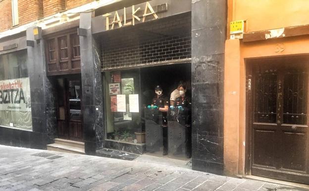 Ertzainas en la puerta de la lonja okupada protegen al operario encargado de tapiar la entrada.