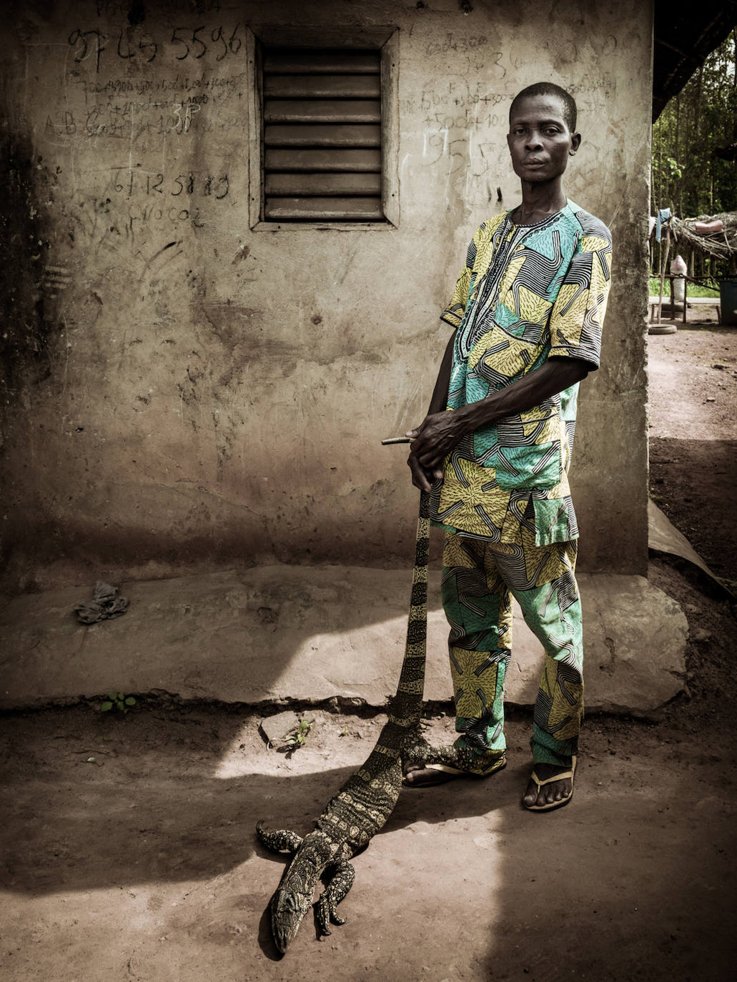 Todo es desmesurado en África, también la fauna. En la imagen, un hombre sostiene un lagarto que ha cazado en las inmediaciones de su casa y que ahora se propone vender.