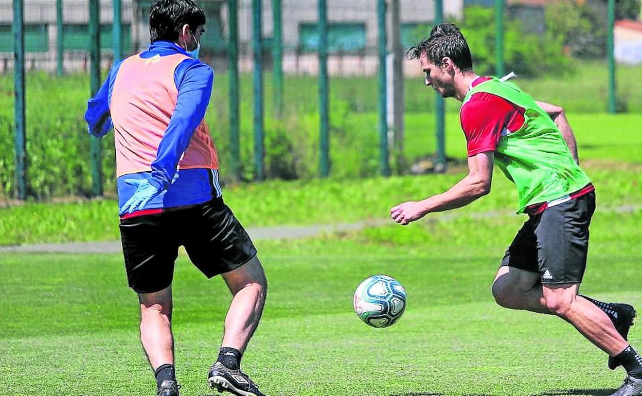 Andoni Iraola, con guantes y mascarilla, aprieta a Lorenzo Crisetig en un entrenamiento.