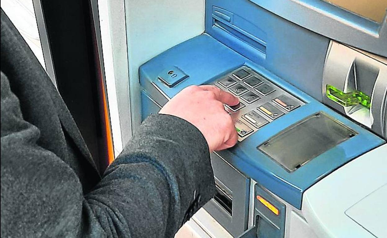 Un cliente saca dinero de un cajero.