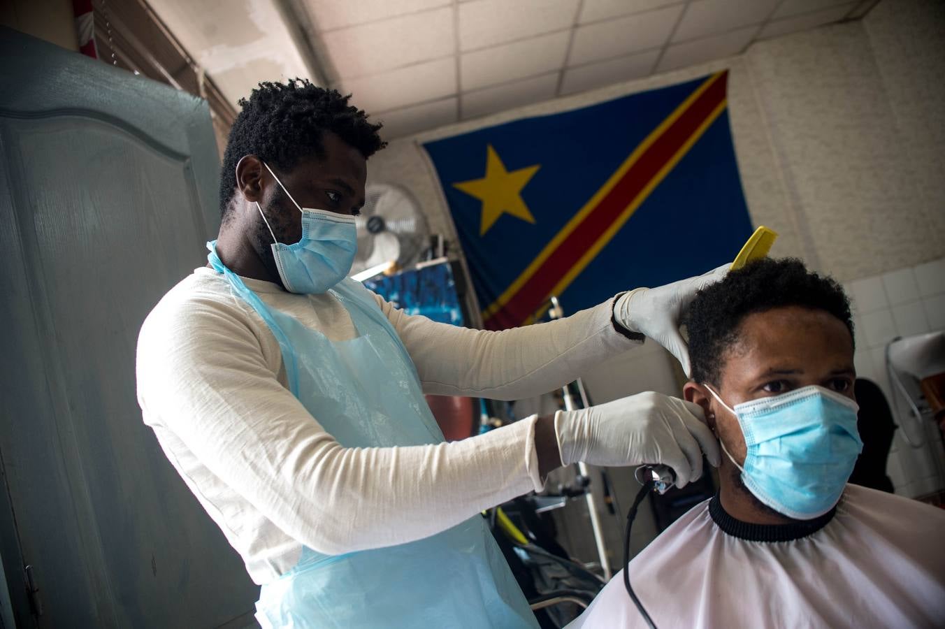 Rodrigo Adri de 32 años cortando el pelo a un cliente en su peluquería de San Francisco.