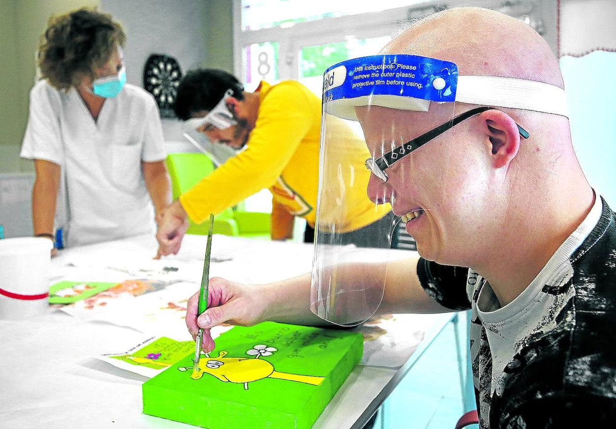 Alex Villanueva, en primer plano y Alex Muñoz, protegidos con pantallas en un taller de pintura.