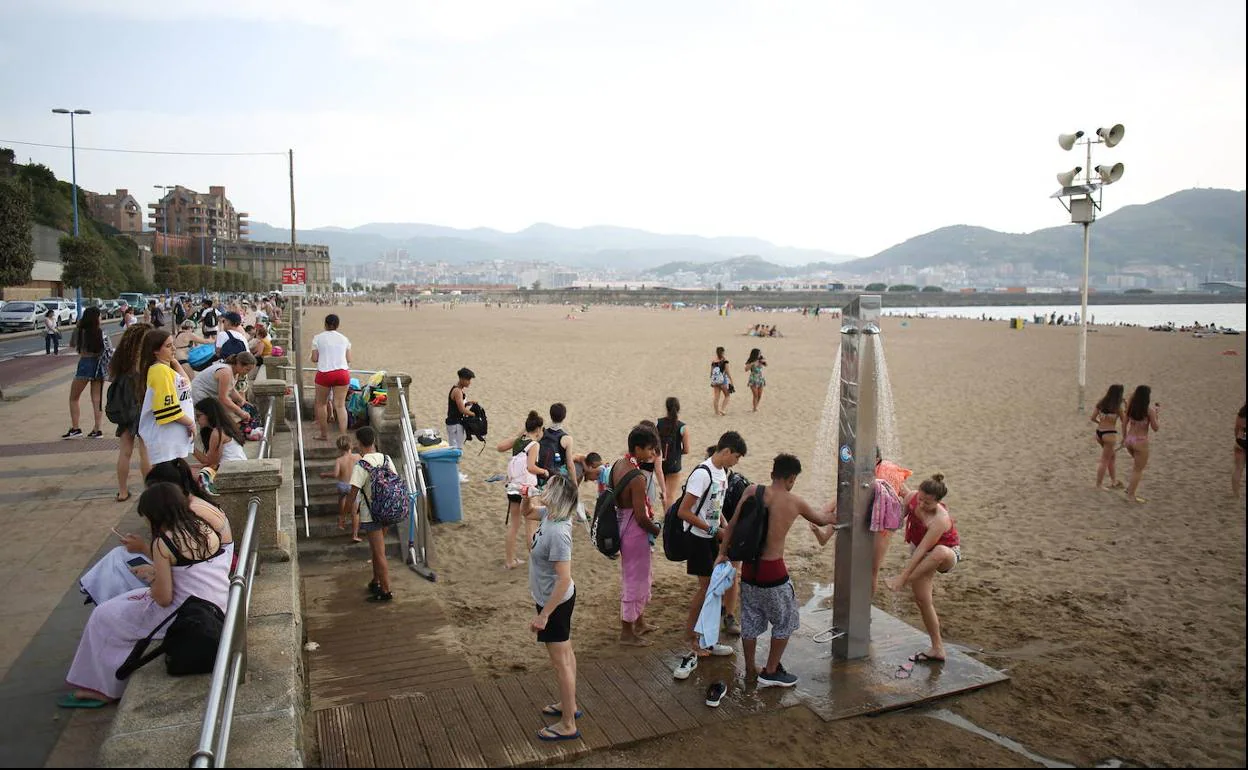 Varias personas duchándose en la playa de Ereaga, imagen de archivo.