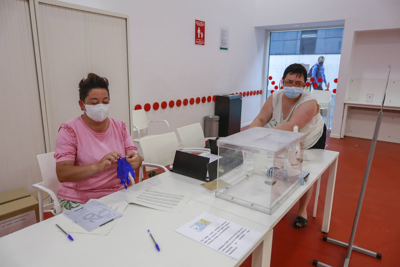 Protegida con mascarilla, la integrante de una mesa se coloca guantes.