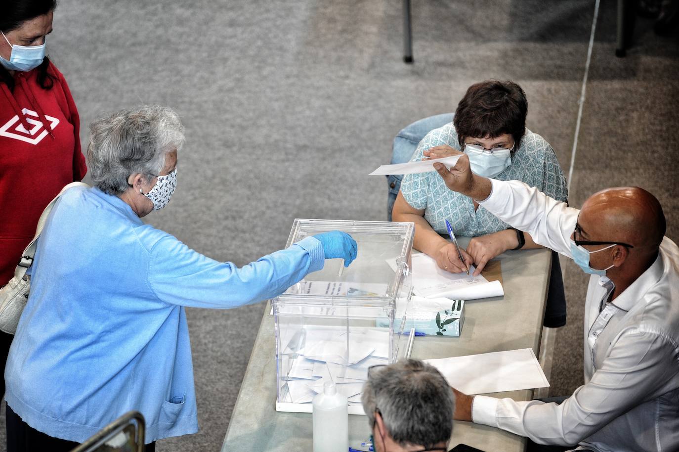 Una mujer vota, protegida con mascarilla y guantes, en el centro cívico Aldabe.