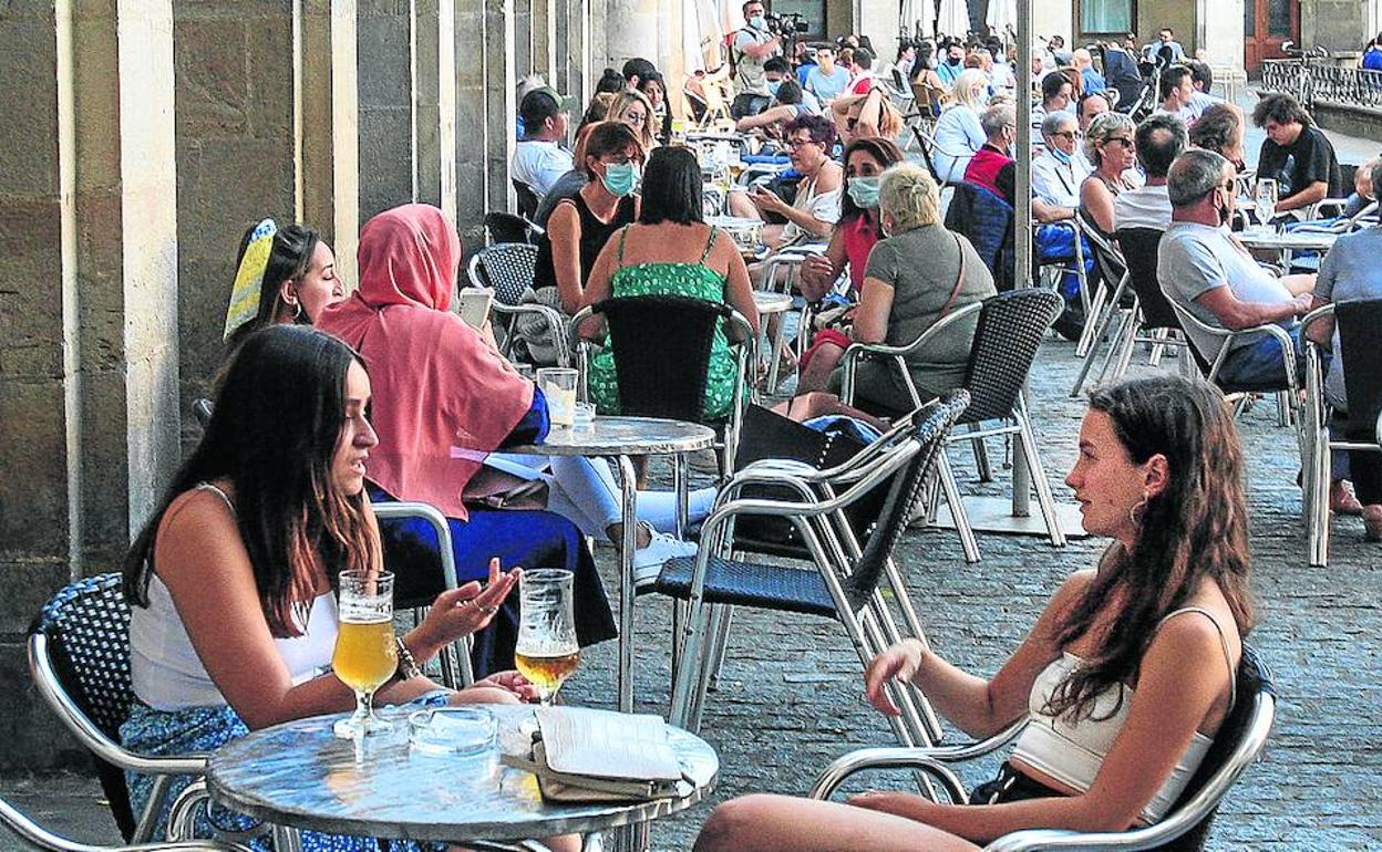 Varias personas toman unas consumiciones en una terraza de la plaza de España de Vitoria.