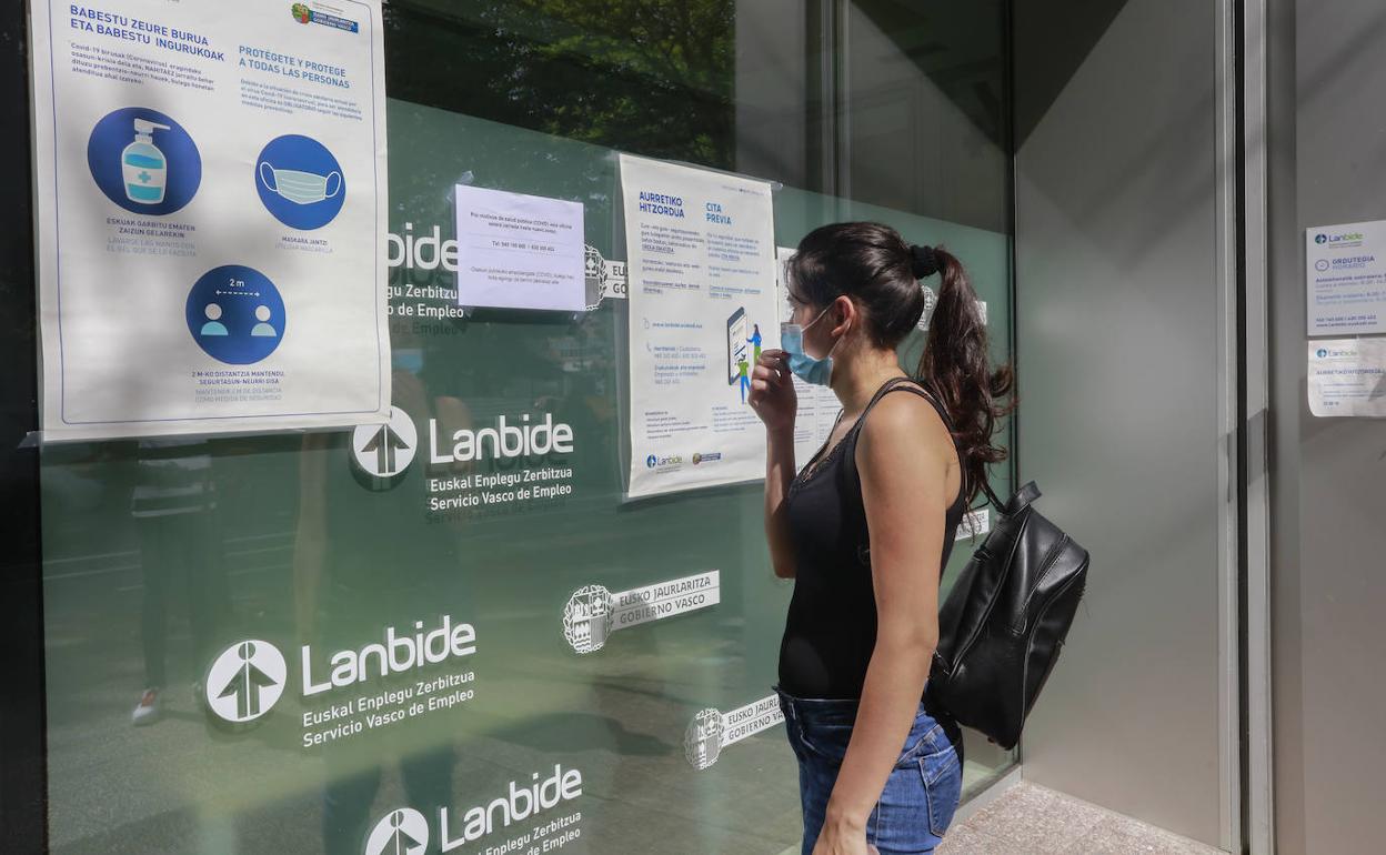 Una mujer lee un cartel en la entrada de una oficina de Lanbide.