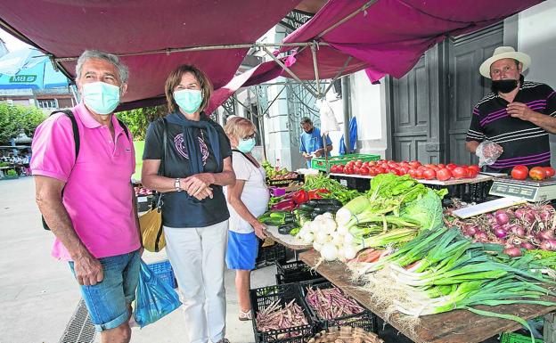 Plaza de abastos. Santi y Carmen compran unos tomates en el puesto de Eduardo. 