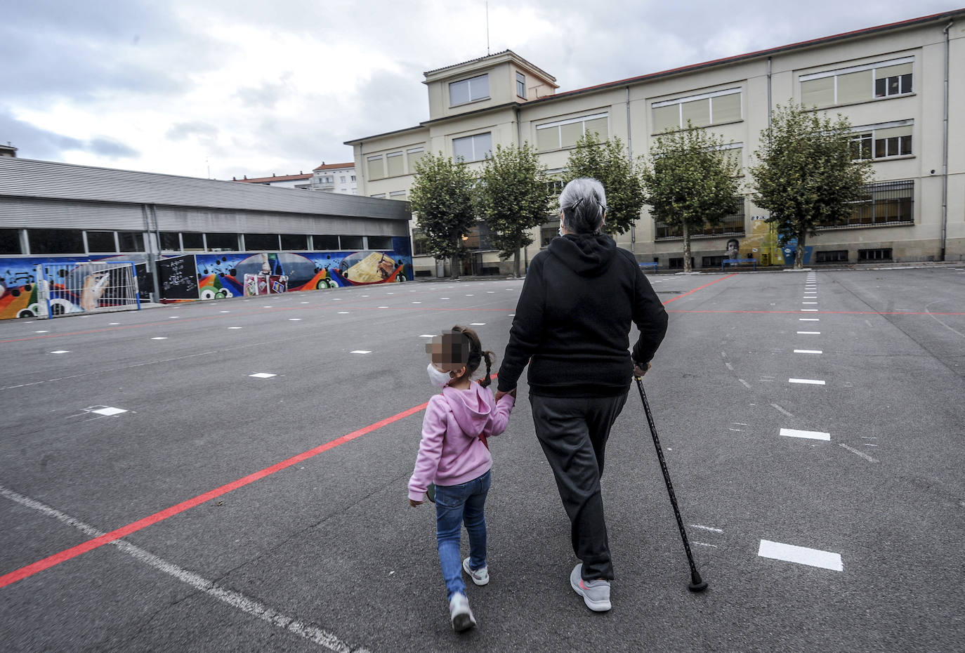 Una niña, protegida por su mascarilla, camina por el patio del colegio Samaniego.
