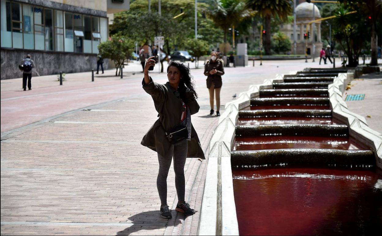 Una acequa que recorre el centro de Bogotá es teñida de rojo para simular la sangre de las víctimas fallecidas en las matanzas que se repiten en Colombia.