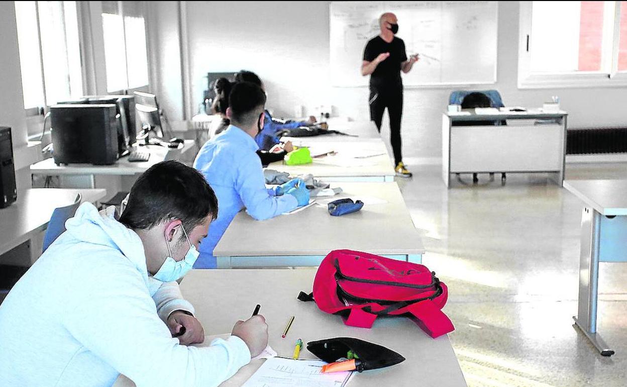 Varios estudiantes asisten a clase con mascarilla. 