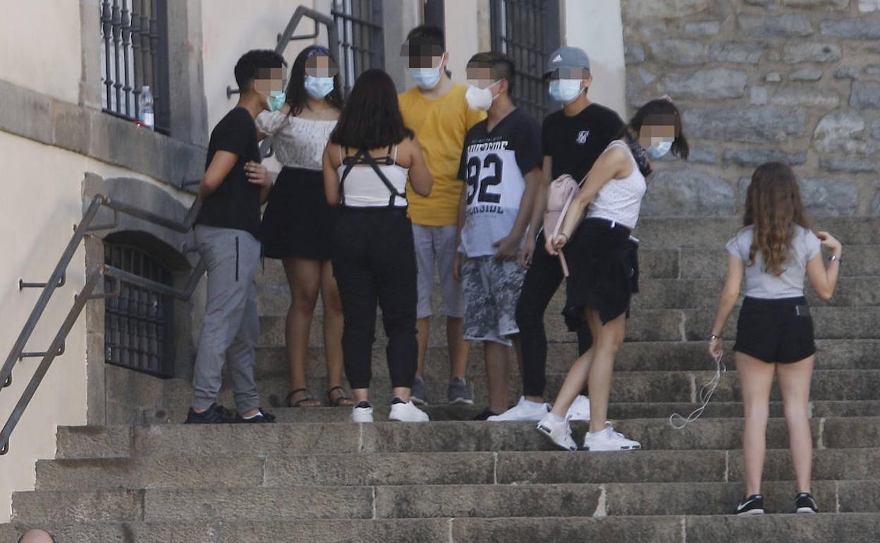 Un grupo de jóvenes protegidos con mascarillas en las escalinatas de San Miguel. 