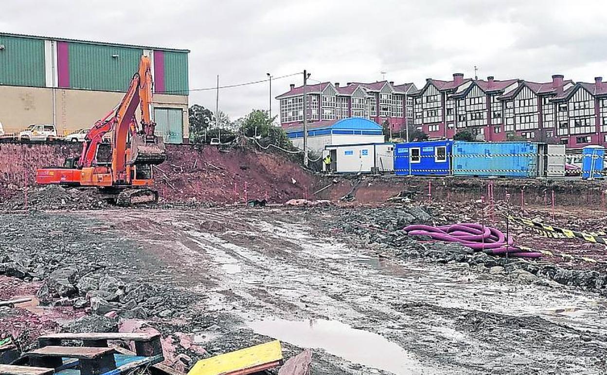 Una excavadora trabaja en la zona, con las casas al fondo.