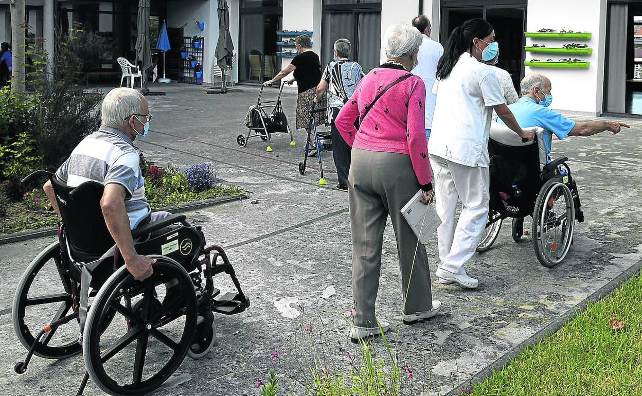 Alojados en una residencia de Bizkaia salen a dar un paseo acompañados de profesionales de la institución. 