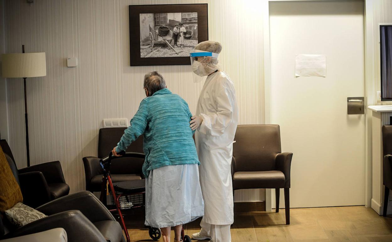 Una cuidadora atiende a una anciana en una residencia. 