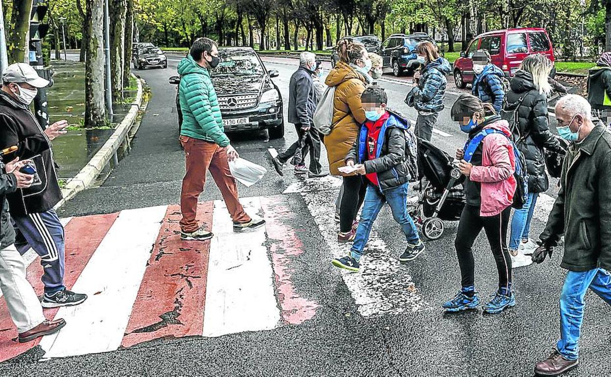 Escolares y adultos atraviesan ayer uno de los pasos de cebra de la calle Iturritxu, a pocos metros del paso donde el miércoles fue golpeado por un coche un menor.