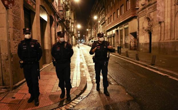 Agentes de la Ertzaintza patrullan por Bilbao La Vieja tras comenzar a las 23.00 horas el toque de queda.