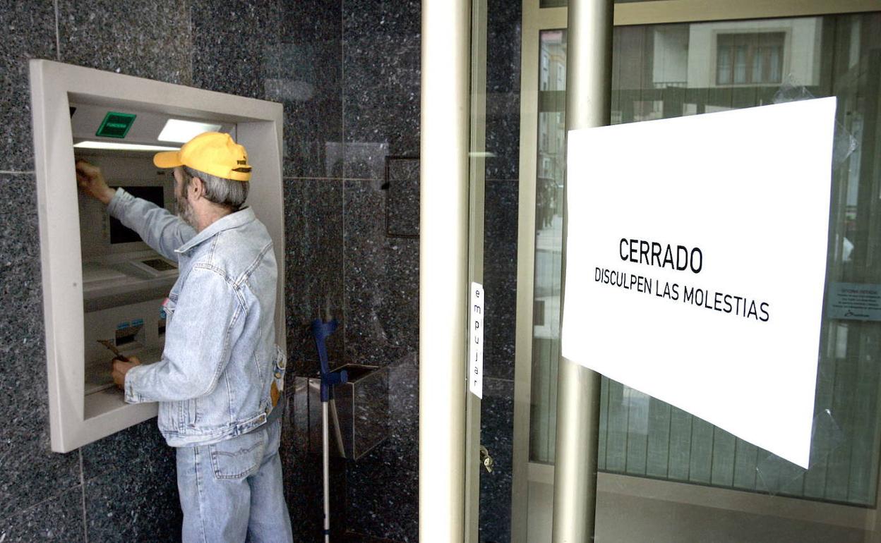 Un hombre utiliza un cajero automático de una sucursal cerrada al público.