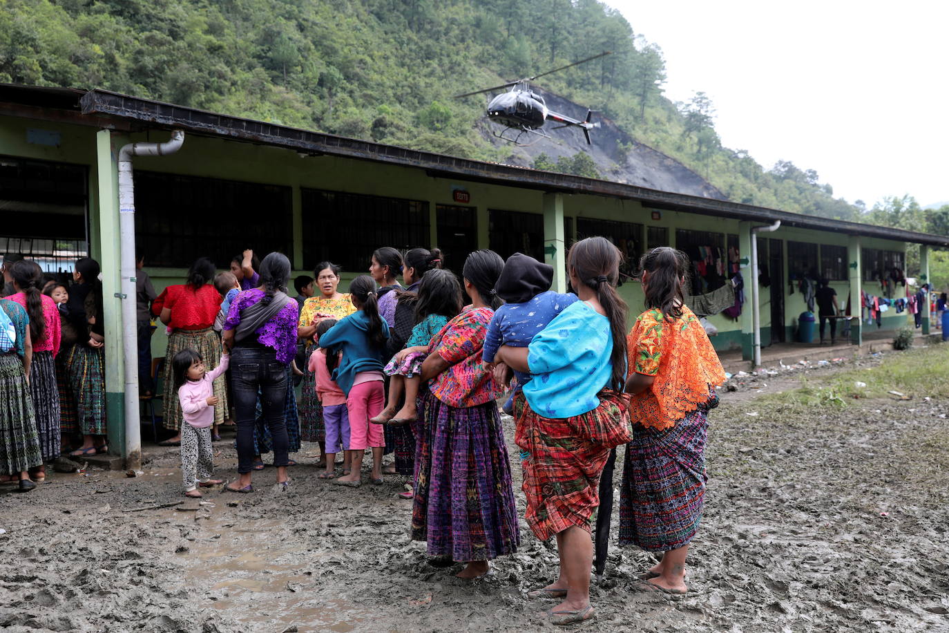 Mujeres observan un helicóptero aterrizando en una escuela, siendo utilizado como refugio temporal para personas de poblados vecinos afectados por los deslizamientos de tierra provocados por las fuertes lluvias traídas por la tormenta Eta, en el poblado de Santa Elena.