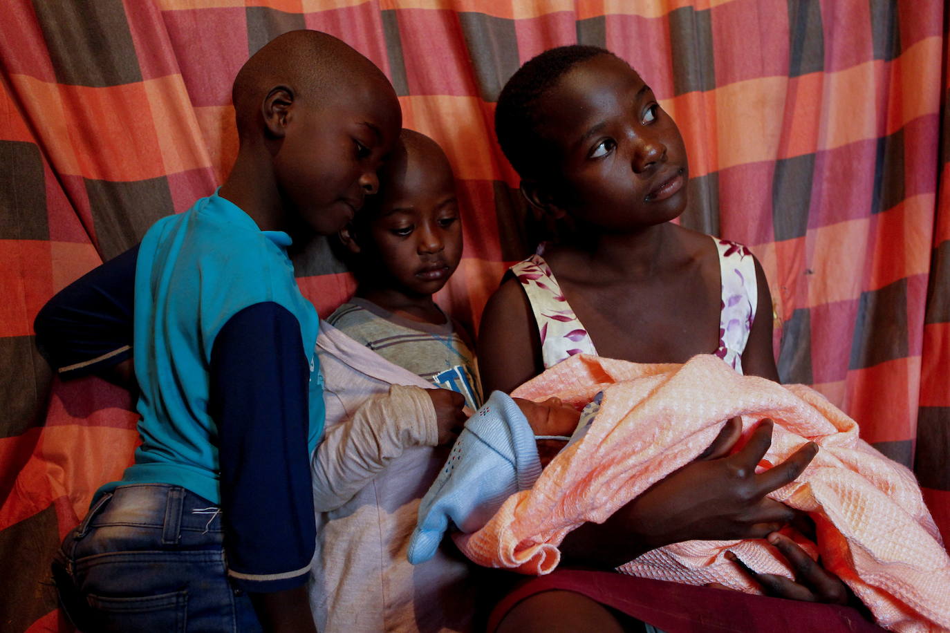 Las hermanas menores de Bosibori, Maurine Bochaderi, de 7 años, Faith Nyakerario, de 5, y Angela Moraa, de 12, pasan tiempo con la hija recién nacida de Bosibori..