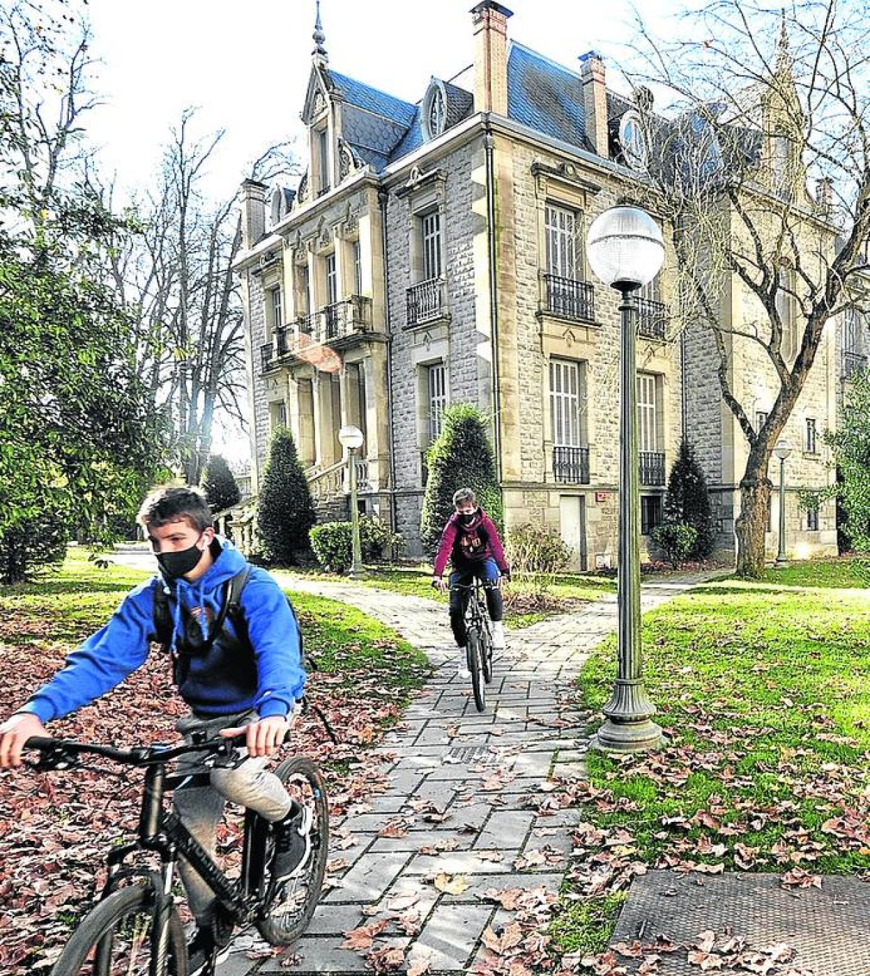Unos jóvenes pedalean por el jardín del edificio, ahora sin uso.