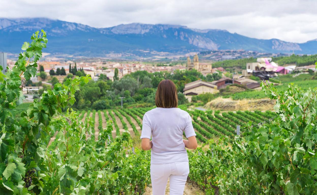 Una mujer observa Elciego y el complejo de Marqués de Riscal, con la sierra de Cantabria al fondo.