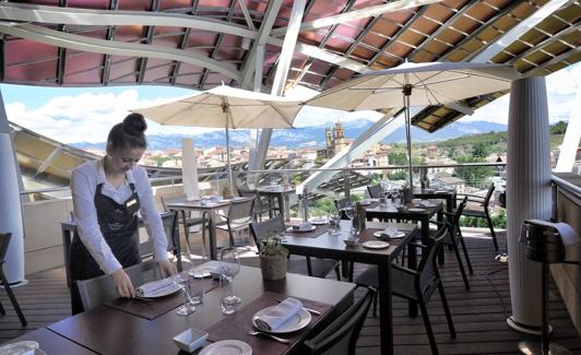 Una camarera prepara una mesa en la terraza del restaurante de Riscal.