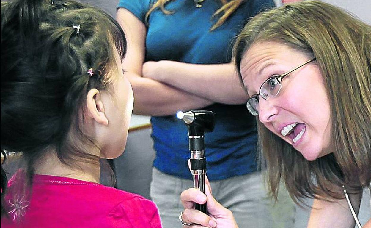 Una doctora revisa a una niña en la consulta. 