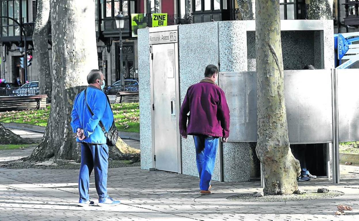 Varias personas aguardan en el baño público instalado en El Arenal de Bilbao. 