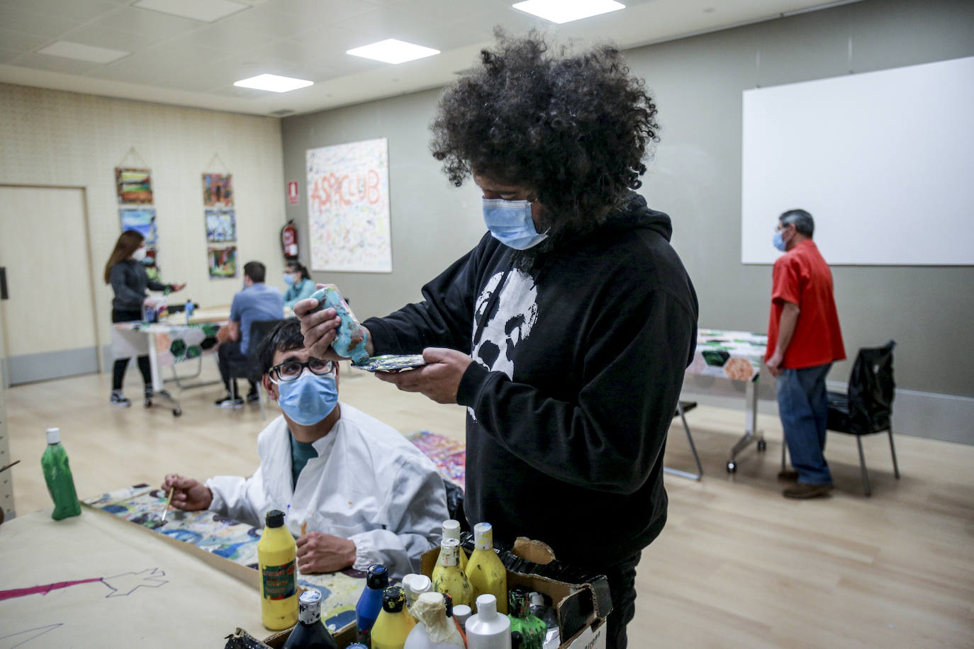 Usuarios y voluntarios participan en el taller de pintura de la asociación de parálisis cerebral Aspace, una de las numerosas actividades de las que disfrutan sus más de 130 miembros.