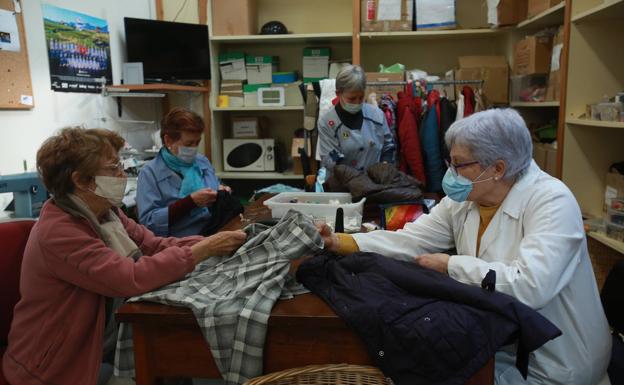 Voluntarias de Cáritas remiendan y acondicionan la ropa donada para Koopera. 