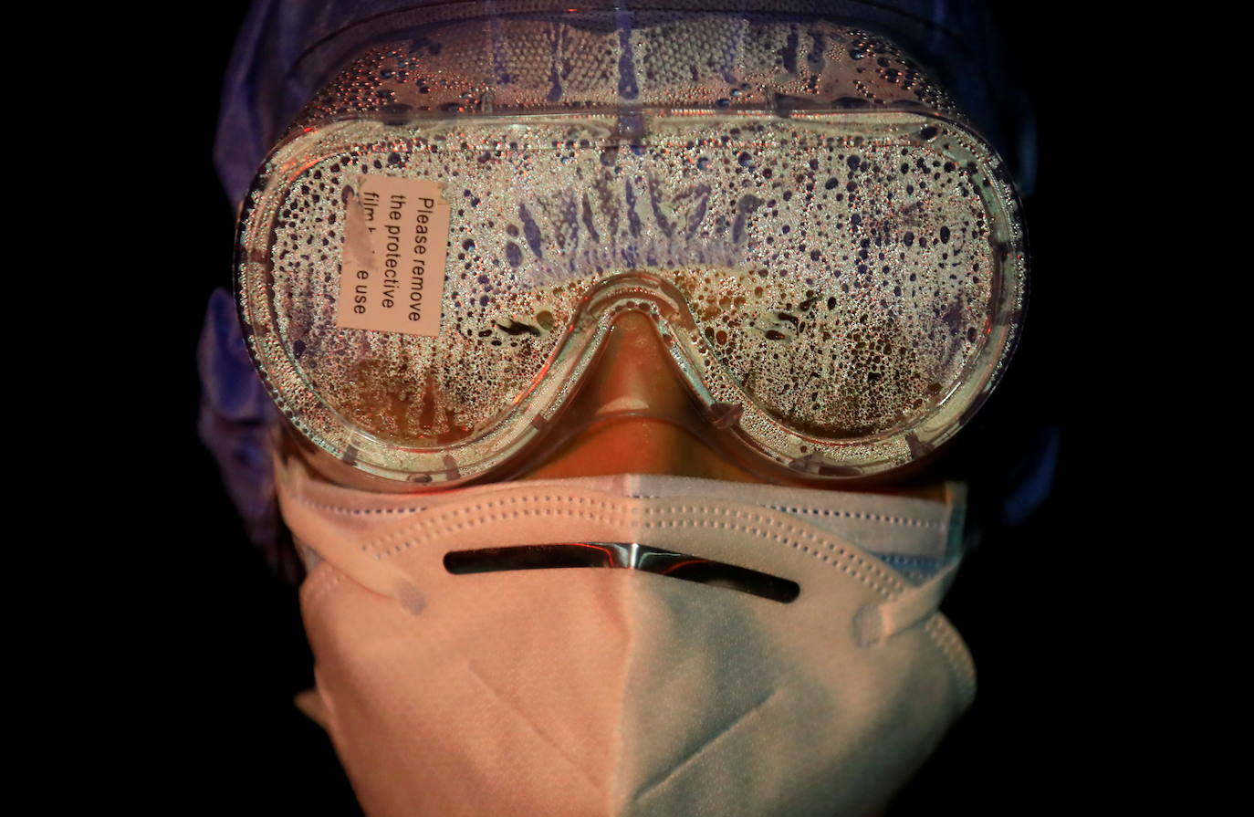 Las gafas de una mujer soldado están cubiertas de vapor después de tocar los cuerpos de las víctimas del coronavirus.