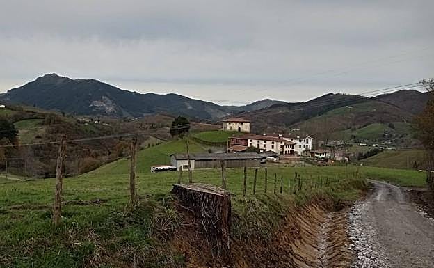 Caserío Etxarte, con la ermita de Santikurutz detrás.