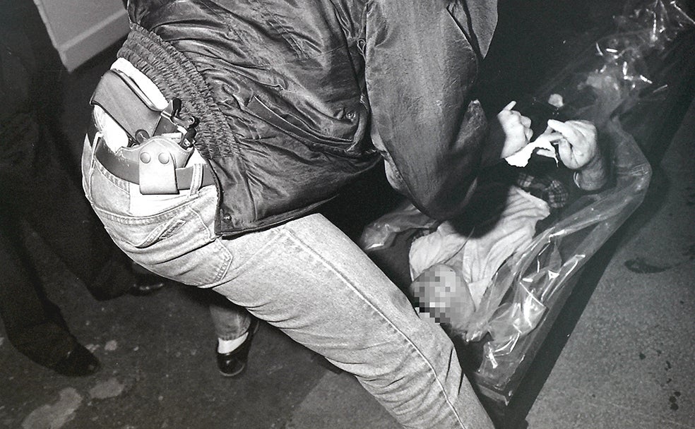 Un policía nacional de paisano trata de identificar mediante la huella dactilar a un hombre muerto en Bilbao.