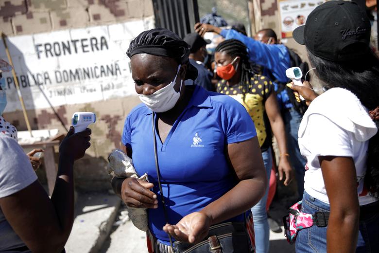 República Dominica. Una mujer proveniente de Haití usa una mascarilla para evitar la propagación del coronavirus mientras le controlan la temperatura y recibe gel desinfectante en la frontera entre Malpasse, en Haití, y Jimani, en República Dominicana, ya que la frontera permanece abierta. con fines comerciales, en Jimani, República Dominicana.