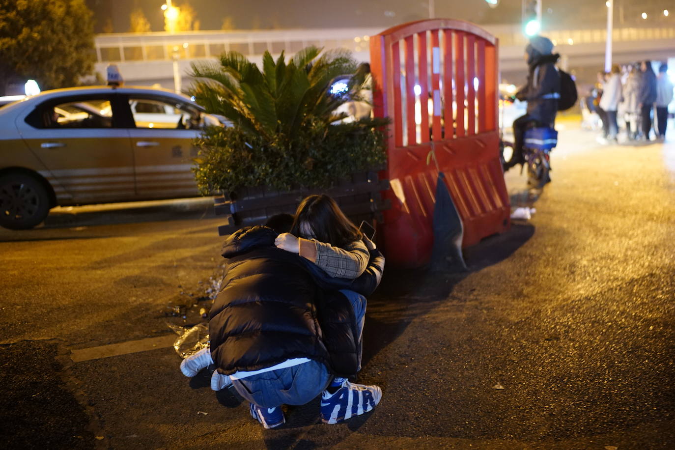 Un hombre abraza a su novia en la calle frente a un club nocturno.