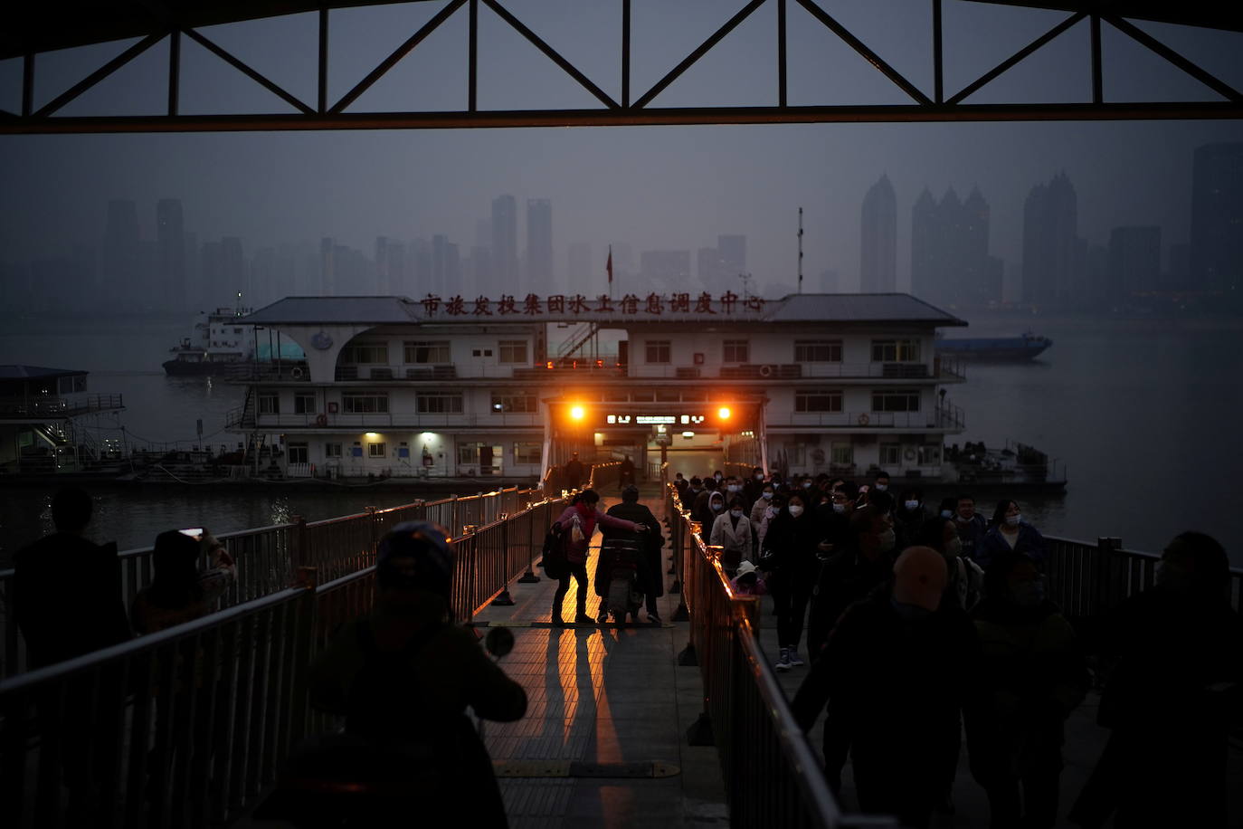 Personas que llevan máscaras faciales salen de un ferry al pasar por el río Yangtze.