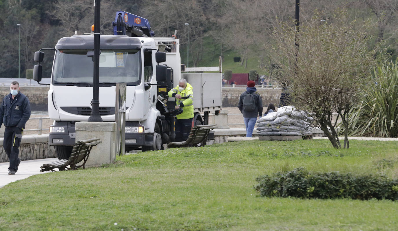 Operarios reparten sacos de tierra para protegerse del temporal de la próxima madrugada.