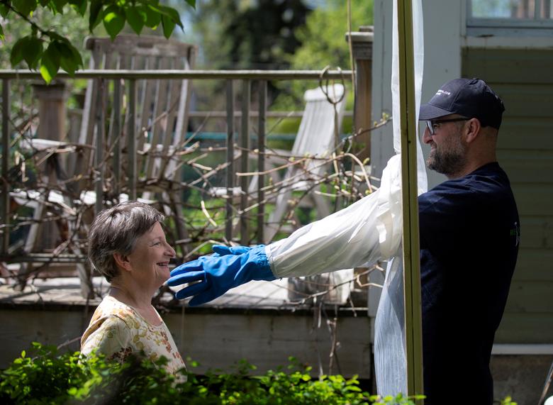 Alex Montagano demuestra su "Estación de abrazos" con la vecina Sharon Pearce-Anderson, que construyó para abrazar a los miembros de la familia con precauciones contra el coronavirus en Montreal, Quebec, Canadá.